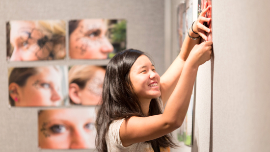 Summer programs student hanging photography prints for critique