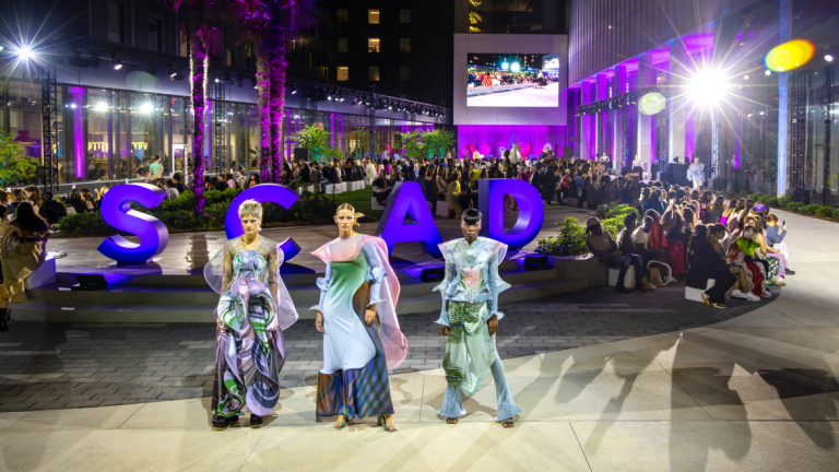 SCAD Fashion Show 2023 models watching a runway in Atlanta at night.