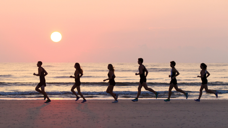 SCAD cross country athletes run across beach at sunset